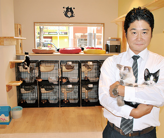 店内で保護猫を抱く井上さん