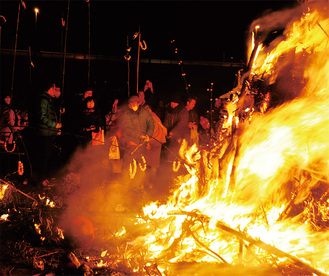 燃え盛る炎で団子を焼く人々（昨年）