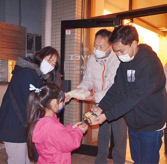 寄贈した食品を手渡す小野岡代表（右）と井上社長