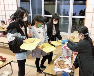 コミュニティ食堂「おにぎり」でピザを取り分けてもらう子どもたち＝中井町境コミュニティセンター