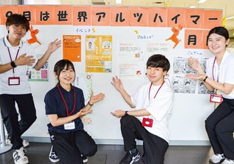 二宮町役場の啓発ブースと設営した実習生（左から木村さん、坂巻さん、込山佳隆さん、砂賀亜美さん）