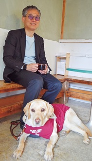 行きつけのカフェ「旅花」で取材を受ける板嶌さんと、盲導犬のテス