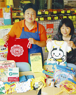 第２便を箱詰めする片山さん（左）と杉山久恵さん（右）。中央の黄色い募金箱が店頭に置かれている