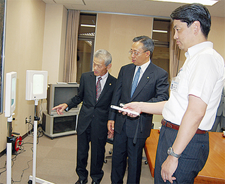 視力検査器を動かす加藤市長（写真中央が田代小田原ＬＣ会長、左が秋山報徳ＬＣ会長）