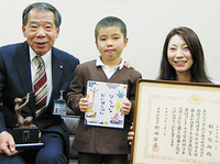 絵本を手にする陽翔君（中）と笑顔の智子さん（右）、前田輝男教育長（左）