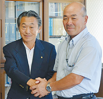 協同体の畠山政則代表と握手を交わす鈴木社長（左）