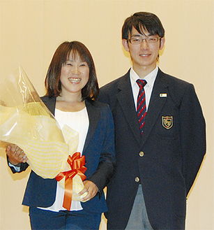 生徒会長の井上直紀君（右）から花束を受け取った尾崎さん
