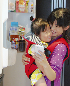 冷蔵庫の中を確認しながらスマホで注文する鈴木幸恵さんと、長女の優芽（ゆめ）ちゃん