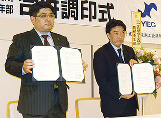 会員に合併調印書を披露する浅野会長（左）と中嶋会長