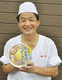 カップ麺を手に笑顔の内田さん