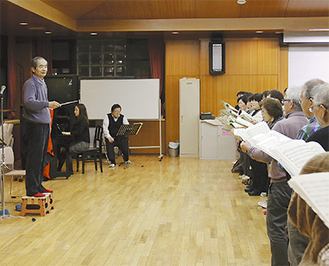 本番を前に合唱団の前で指揮する、『土の歌』作曲者の佐藤眞氏（左）