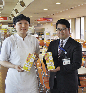 手作りの啓発ポップを持つ、食堂の松井美香店長（左）と環境政策課の大坪覚さん