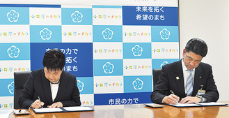 協定書にサインする加藤市長（右）と吉田学長