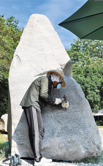 巨大な小松石にノミを入れる、アーティストの北川太郎さん