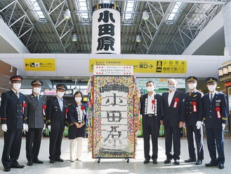 再掲された巨大提灯と折鶴アートを前にする高史さん（右から４番目）ら関係者