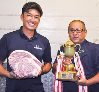 最優秀賞のトロフィーを掲げる長崎代表（右）と受賞牛の肉を持つ中川専務