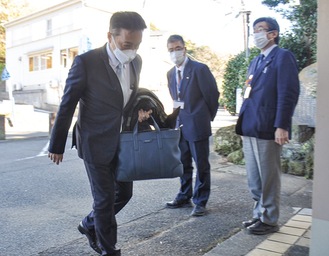 職員に一礼し、庁舎に入る松本町長（左）