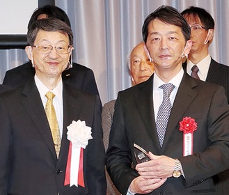 山川鉄郎理事長（左）から盾を受け取る川邉さん