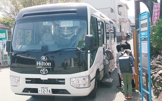 根府川駅前でヒルトン小田原リゾート＆スパのバスに乗車する児童ら