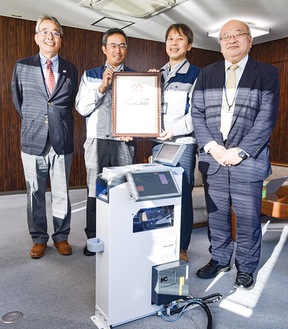 運賃収受機と（左から）丸山社長、管理部の森田貴洋さん、鈴木さん、技術部長の田中廣介さん