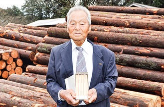 小田原産のヒノキで作った鉛筆を持つ小泉代表理事組合長