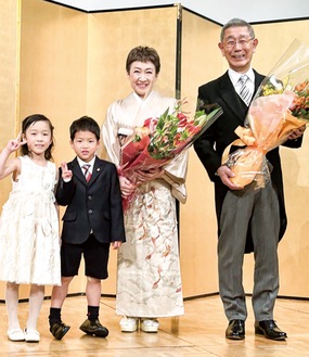 孫から花束を受け取り笑顔の横田医師と妻・佳余子さん