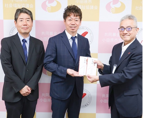 寄付金を手渡す秋山社長(中央)