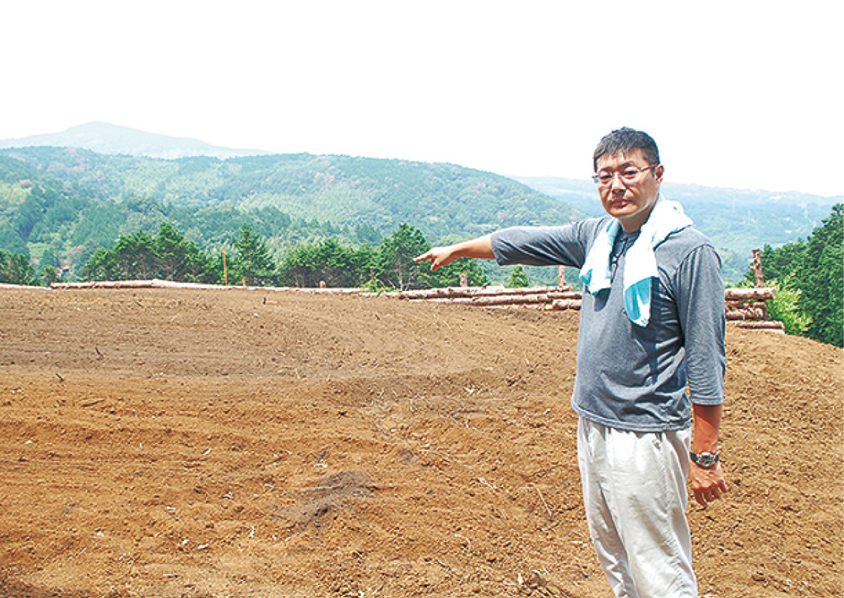 切り拓いた畑を指す久下さん