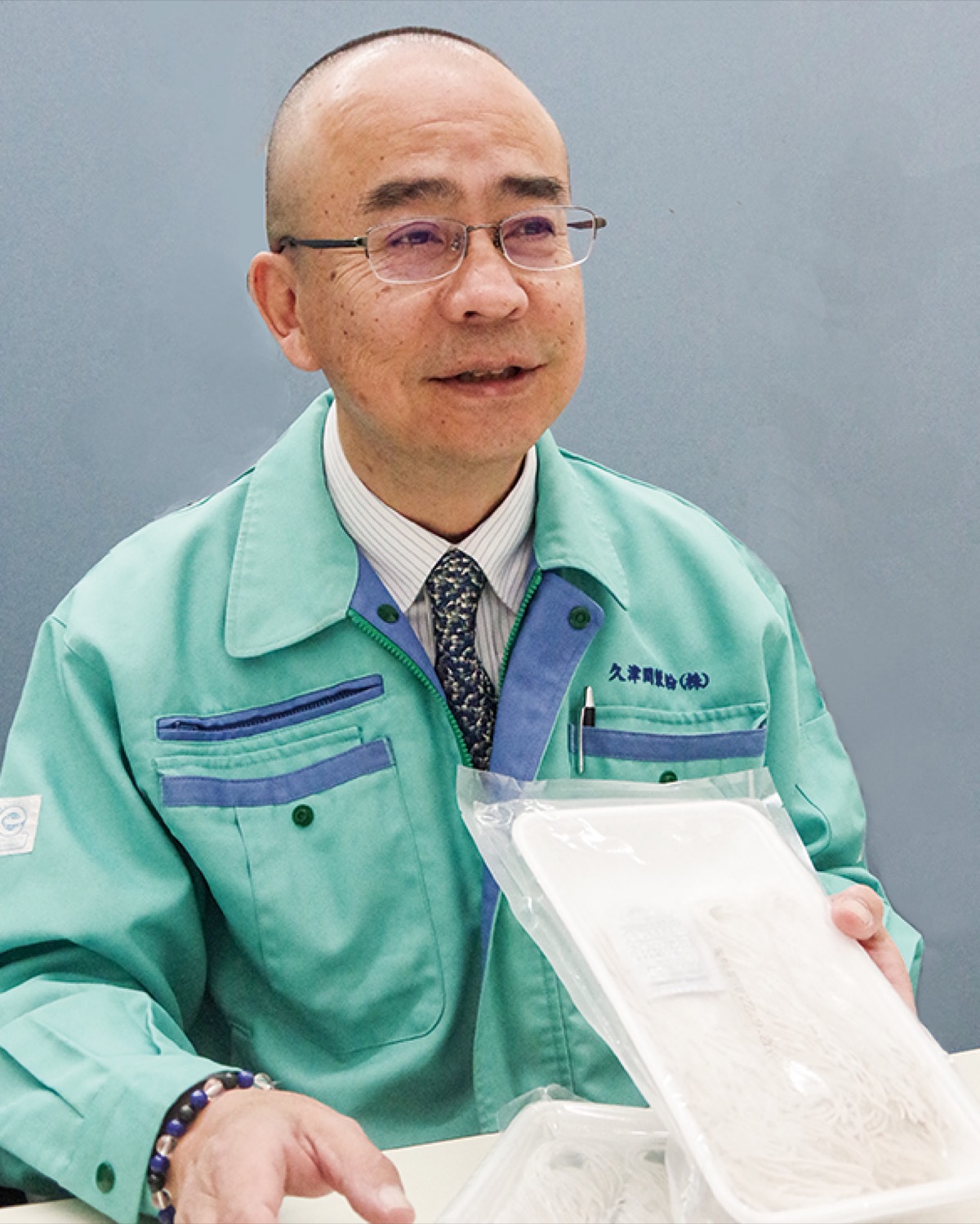 新工場で製造が始まる冷凍そばを手にする久津間社長