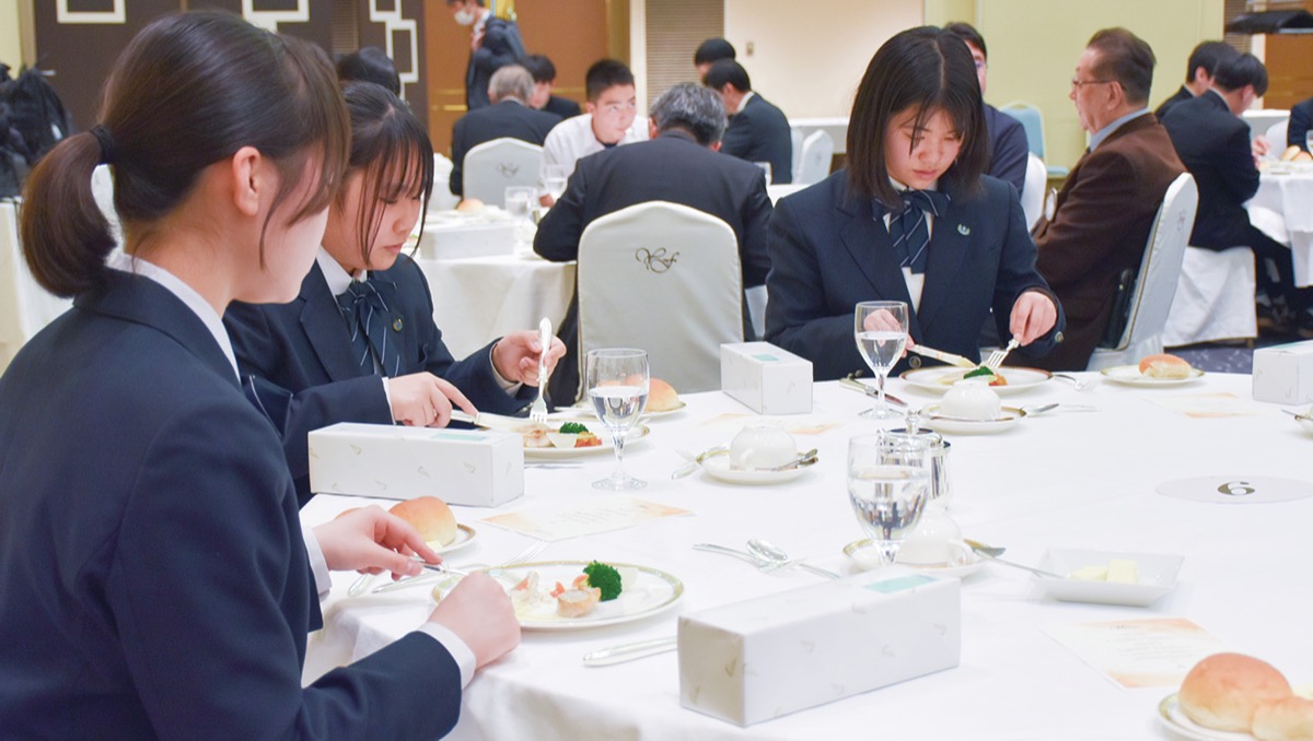 フォークとナイフで食事を楽しむ生徒ら