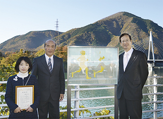 丹沢湖畔に設置されたガラスの記念碑。右から、湯川町長、尾崎孝さん、制作者の冨樫葉子さん