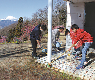 富士山と桜を背に掃除する児童たち＝おおいゆめの里