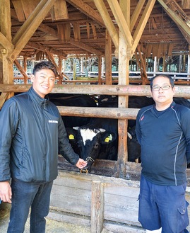 飼育中の相州牛の前で入賞を喜ぶ長崎代表（右）と中川さん