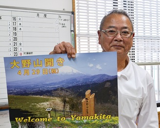 山開きのポスターを手にする依田事務局長