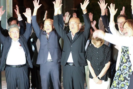 当選を決め、バンザイする本山氏（中央）と支援者ら