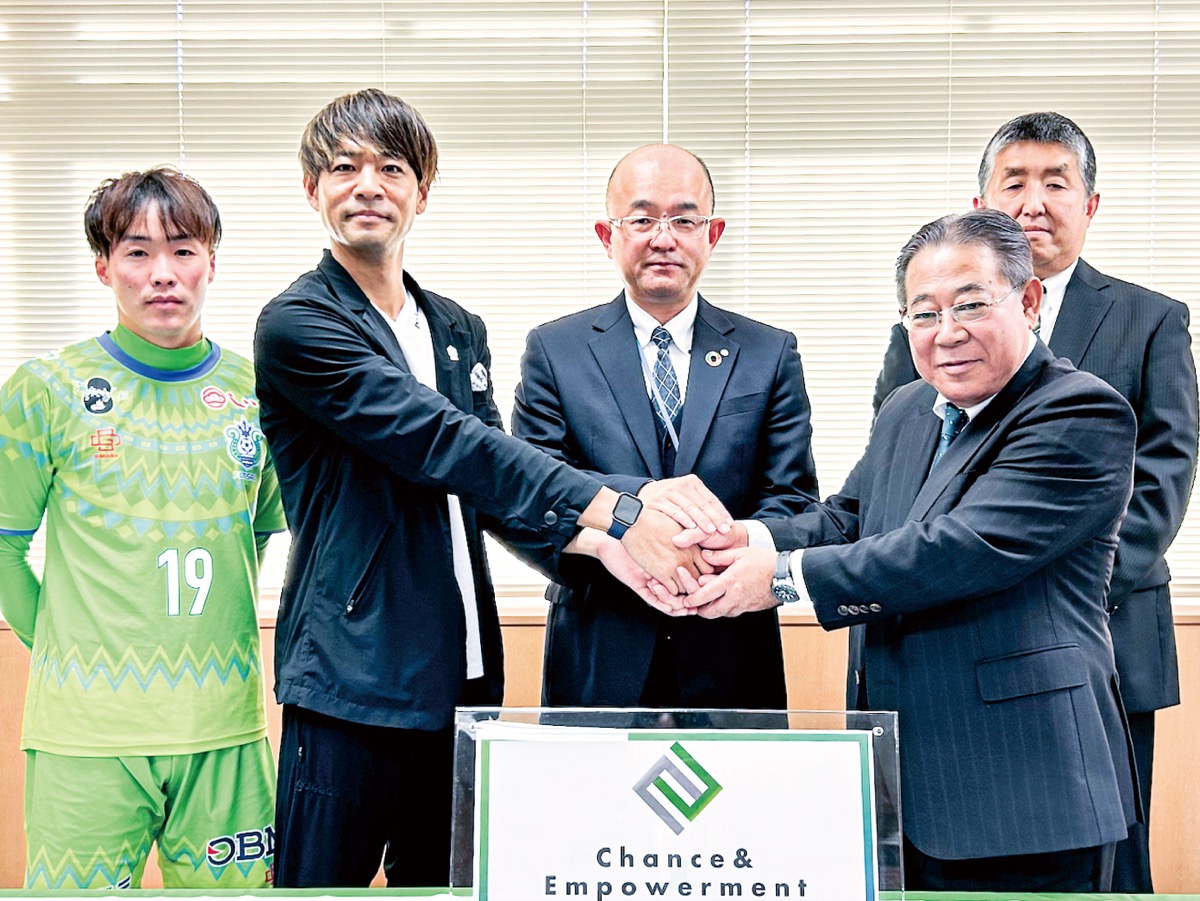 本山博幸町長を中心に手を取り合う佐藤氏(左)と柏手氏