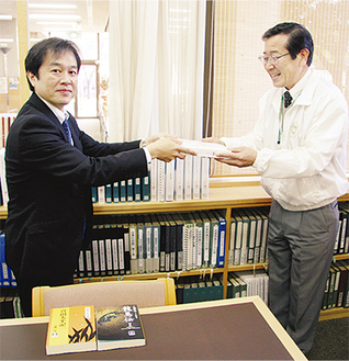 和田館長（右）に寄贈図書を手渡す梶副支社長
