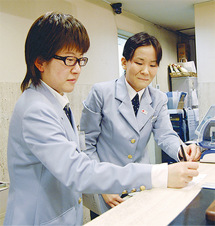 ホテルのフロント業務を行う斉藤さん（左）