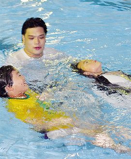 コーチから服に空気を入れて泳ぐ方法を教わる子どもたち（７月１９日撮影）