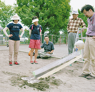 校庭の砂場で堆積実験を行う参加者