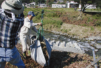 収穫した稲は吉田会長自作の滑車で対岸へ運ぶ