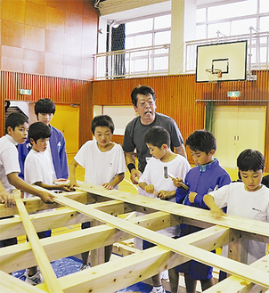 谷さん（中央）の指導を受けながら丹沢産ヒノキを組み上げる生徒たち