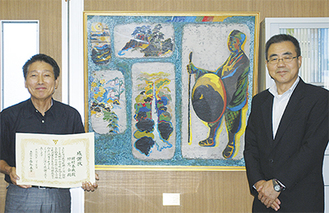 大根中の感謝状贈呈式後、寄贈した絵画の前で笑顔を見せる岡村さん（左）と内田教育長。作品は「造化の天工（松尾芭蕉　奥の細道より）」