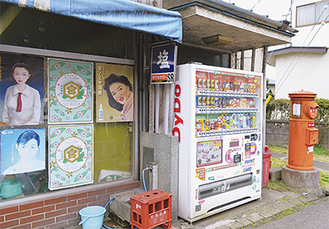 懐かしいデザインのポスターと丸型ポストのある風景