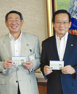 石田理事長（右）が市庁舎を訪れ、古谷市長に見本を手渡した