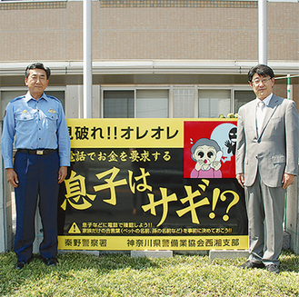 警察署前に設置された看板を挟む、平井支部長（右）と齋藤署長