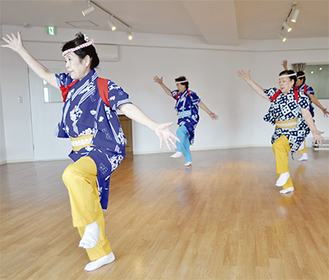 陽気な音楽に合わせて足を高く上げ、手先を広げて踊る櫻川さん（右）ら