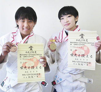 賞状とメダルを掲げる府川さん（右）と飯田さん