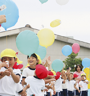 100個の風船を空に飛ばし、周年を祝う園児ら