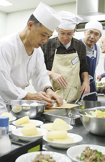 棒寿司の巻き方を教える井上さん（左）